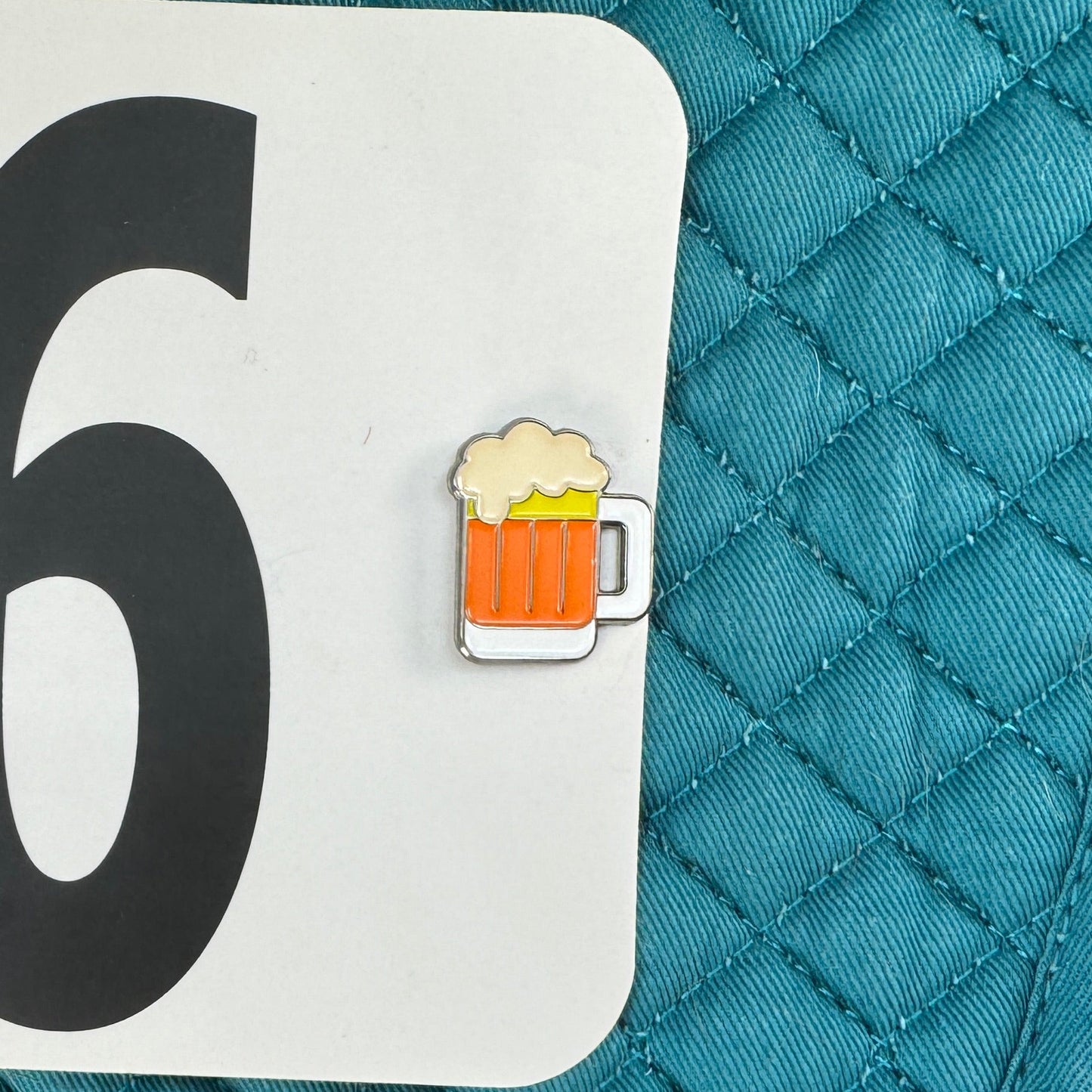 Teal quilted saddle pad with number 96 and a beer mug icon on a white label.