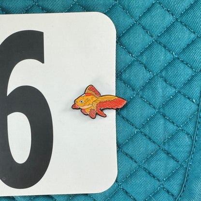 Teal quilted saddle pad with number 96 and goldfish sticker on a black background